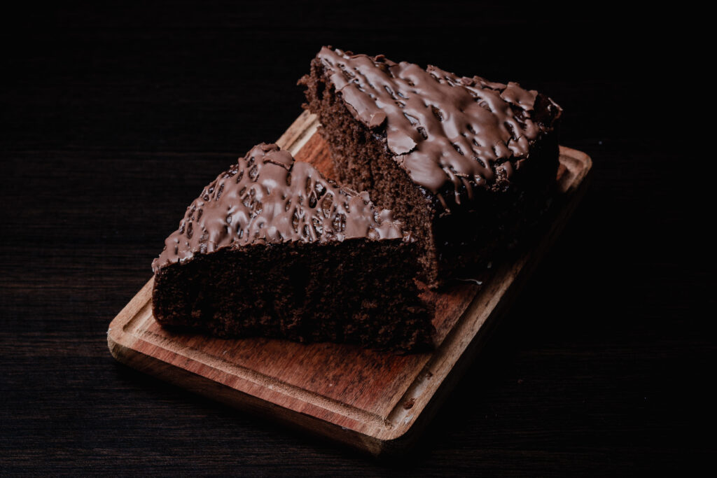 A closeup of two pieces of tasty chocolate cake on a wooden board