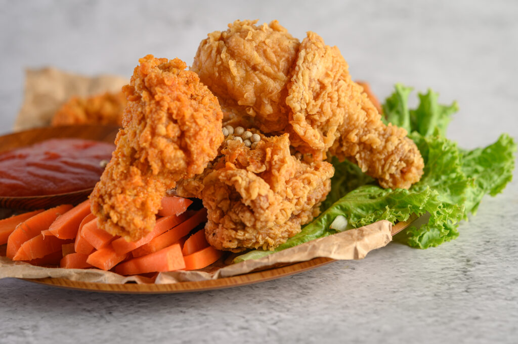 Crispy fried chicken on a plate with tomato sauce and carrot, Selective focus.