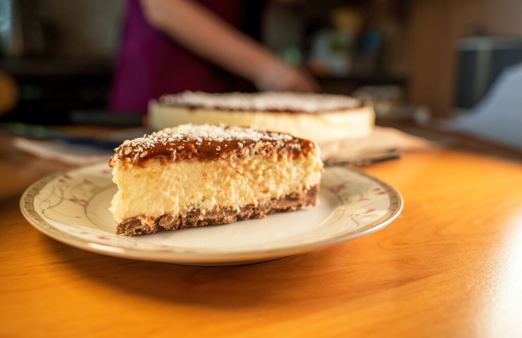 Pieces of a bounty chocolate cocoa creamy cake with coconut and grated biscuit as base being served on a table.